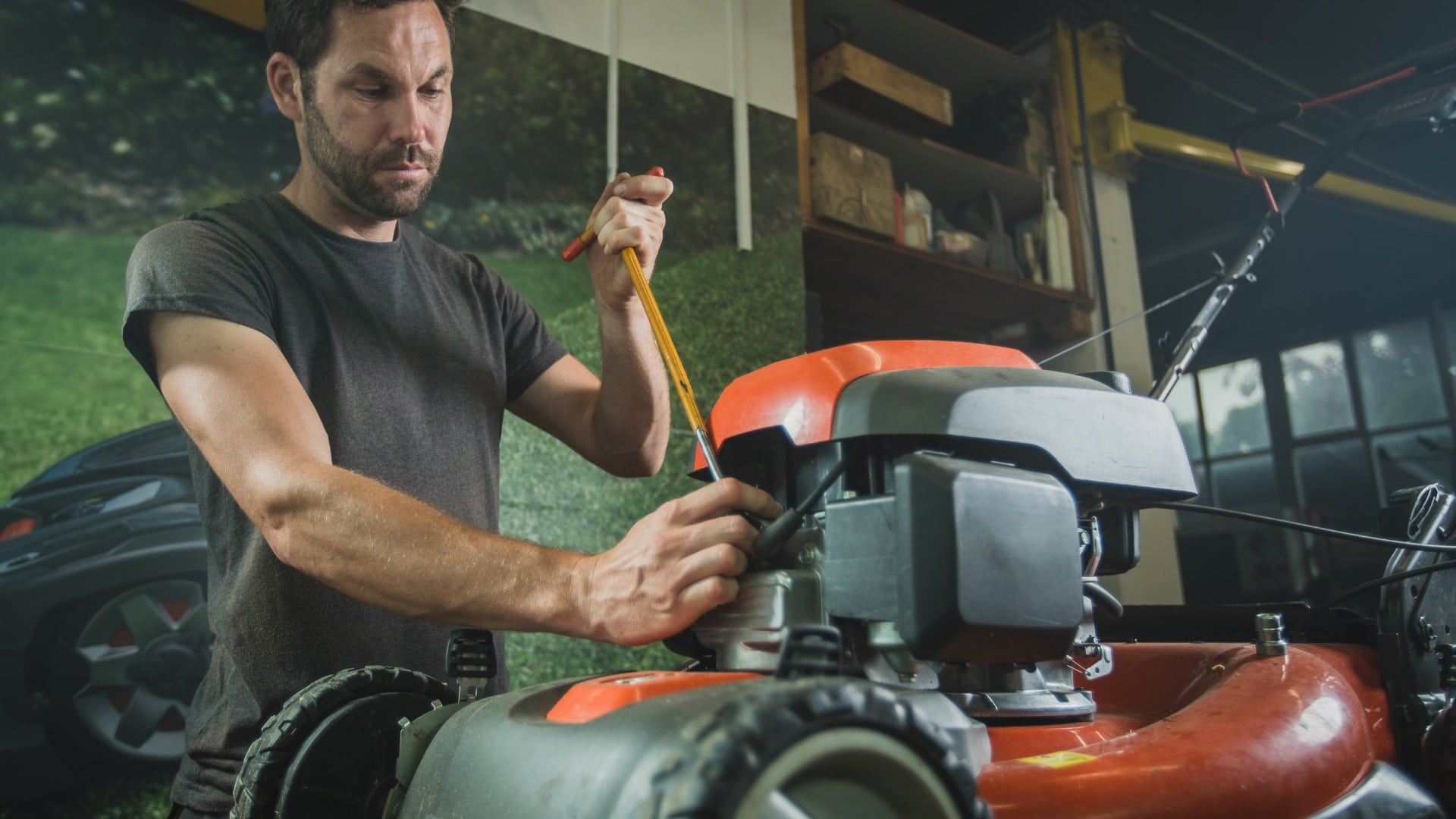 Professional serviceman is repairing a lawnmower, unscrewing a spark plug. Man repairing a mower in a workshop